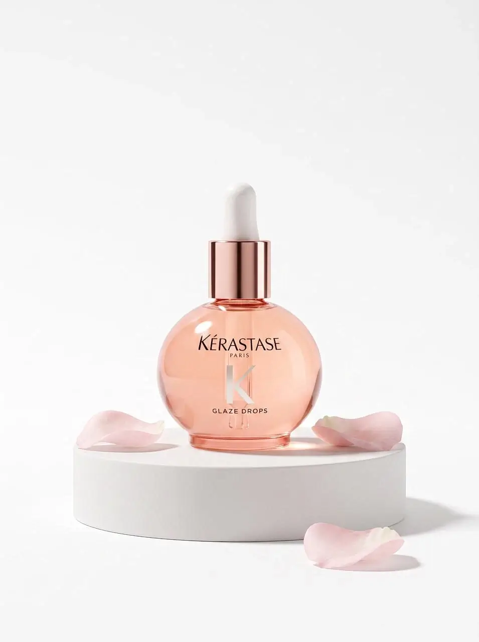A bottle of aromatic oil stands on a stand with rose petals