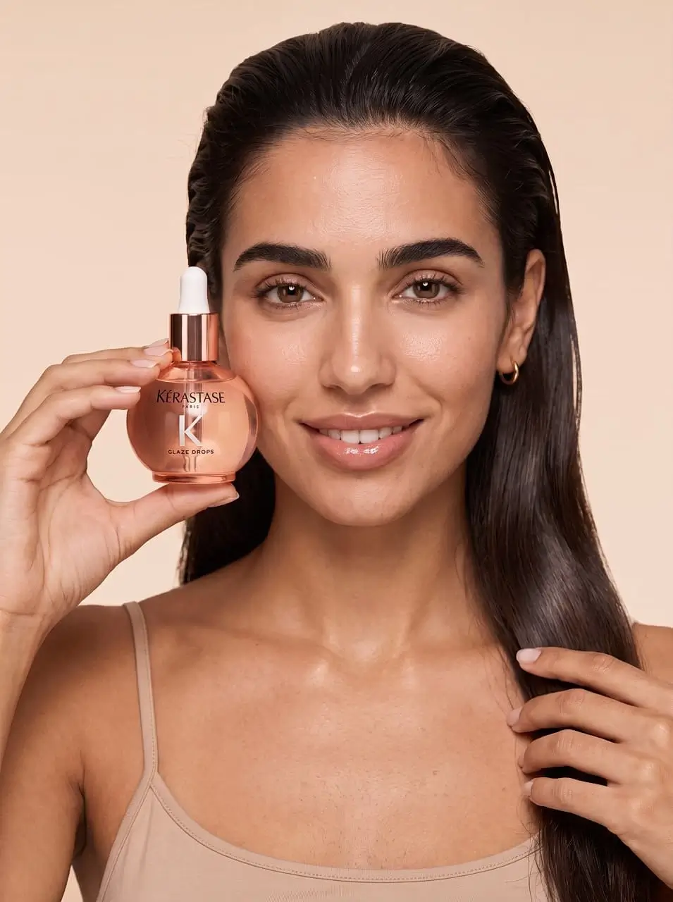 A girl demonstrates a bottle of aromatic oil Kérastase Glaze Drops