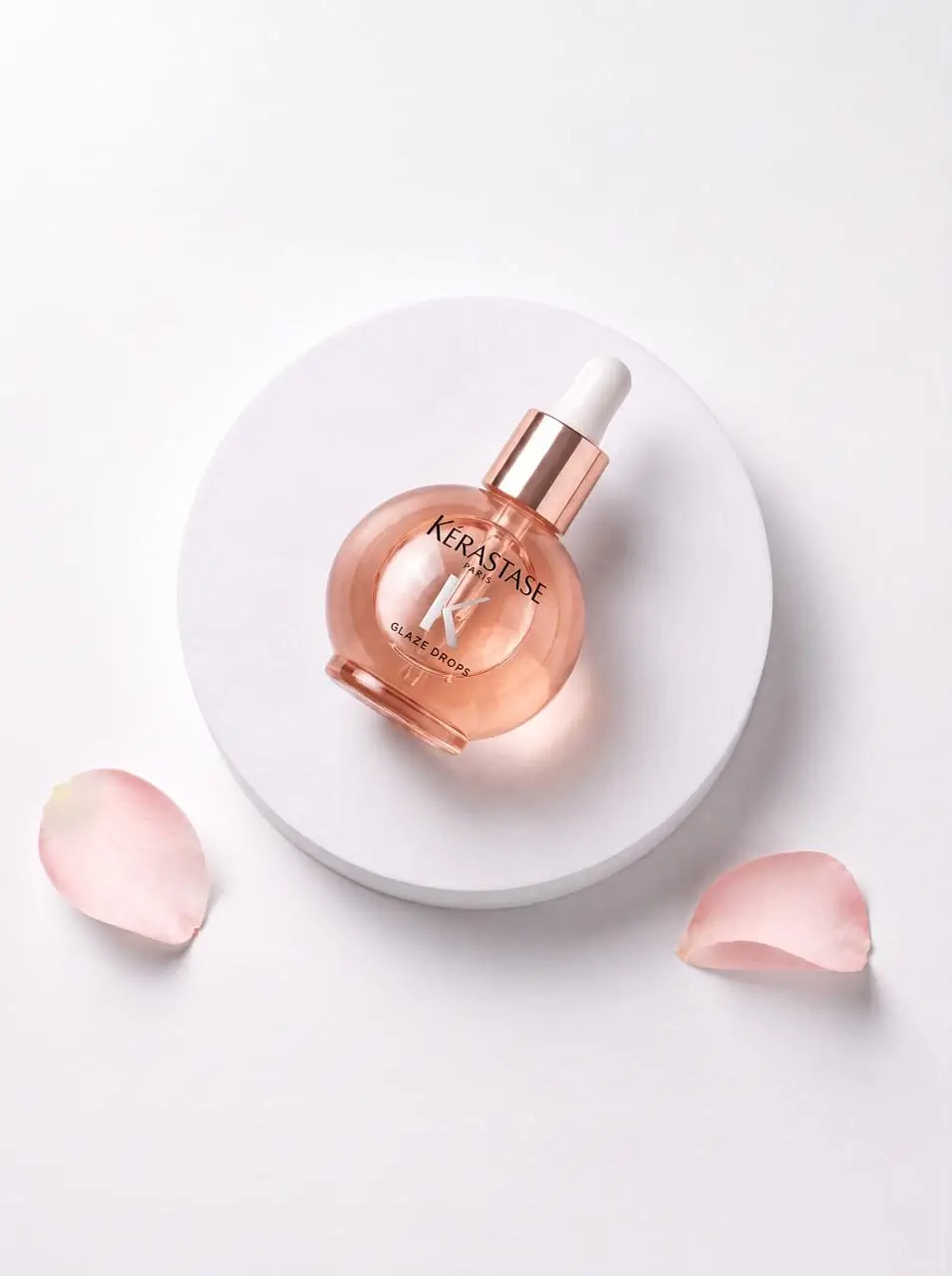 a bottle of aromatic oil Kérastase Glaze Drops lies on a stand